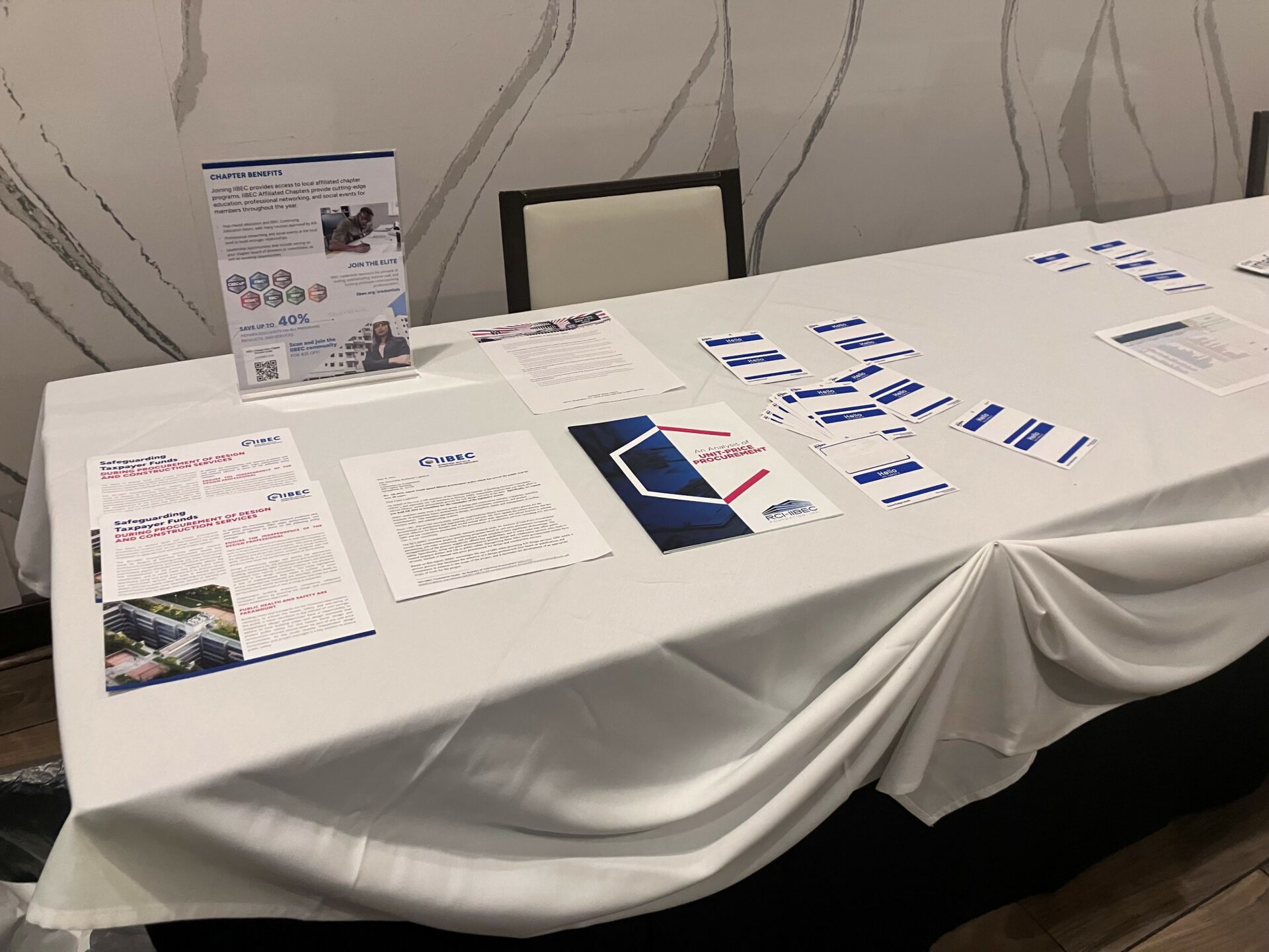 Long table covered in IIBEC marketing materials.