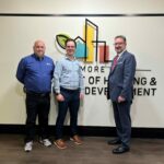 Frank Krech, Mark Howell, and John Boling advocating for facade inspections in front of the Baltimore Dept of Housing & Community Development sign.
