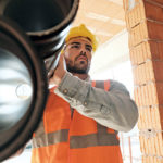 latino worker carrying pipes